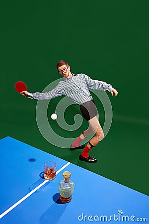 Top view. Funny creative photo with man un shirt and underweared playing table tennis with whiskey glass over green Stock Photo