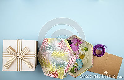top view of a gift box tied with bow and a gift box filled with colorful chrysanthemum flowers with daisy and purple ribbon with Stock Photo