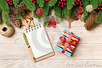 Top view of gift, notebook, Christmas toys, decorations and fir tree branches on wooden background. New Year holiday Stock Photo