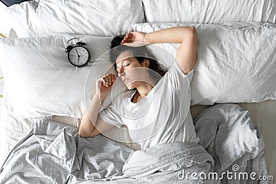 Top view of a girl sleeping next to an alarm clock. Time to wake up. On the wake-up clock 7 a.m. Deep sleep Stock Photo