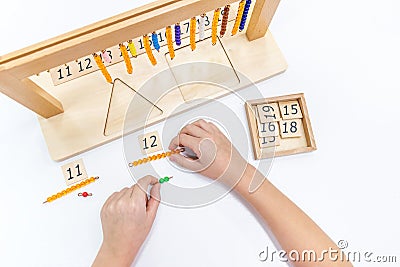 Top view of girls hand is sorting a puzzle of colored wooden geometric shapes in montessori school Stock Photo