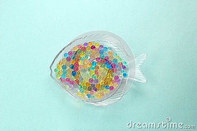 glass plate in the shape of a fish filled with colored balls of aqua grunt, ocean pollution microplastics concept Stock Photo