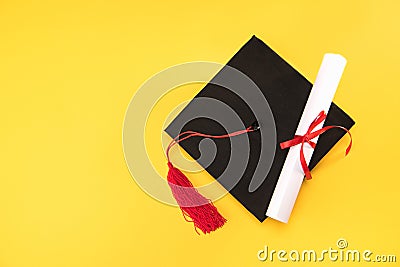 Top view of graduation mortarboard and diploma on yellow background Stock Photo