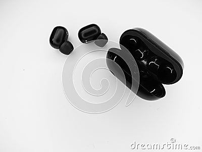 Top view grayscale of wireless earbuds with a black open powerbank on a white background Stock Photo