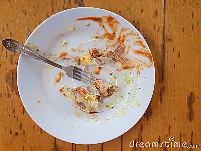 Greasy plate with lonely fork, bread and omelette leftovers Stock Photo