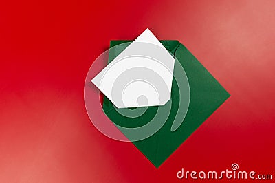 Top view of green envelope, white card on red background. Stock Photo