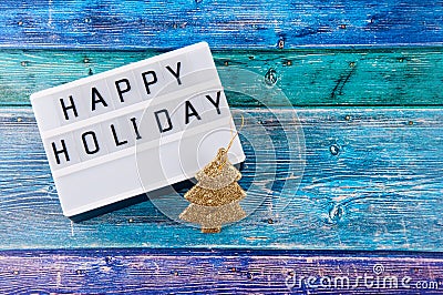 Top view on greeting board with happy holiday wishes and small golden decorative pine tree Stock Photo