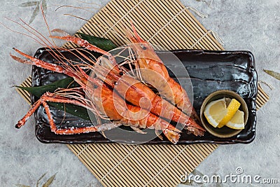 Top view of Grilled shrimps Giant Tiger Pawn with salt served with sliced lemon in black stone plate on makisu Meal mat Stock Photo