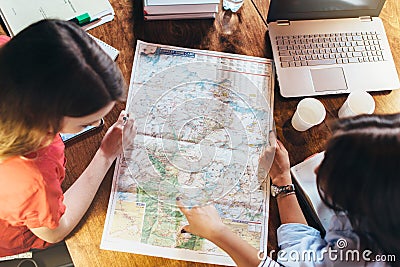 Top view of group of female students studying the map sitting at desk Stock Photo