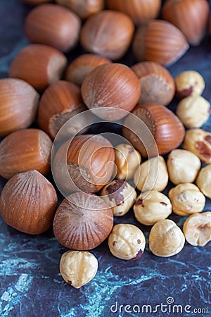 Top view of a group of hazelnuts, whole and peeled out of focus on focused blue marble background Stock Photo