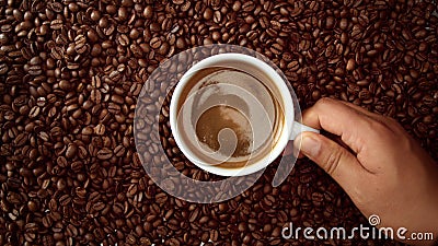 Top view of hand with cup of black coffe put it on coffe beans background Stock Photo