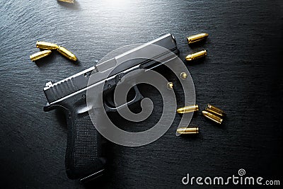 Top view of hand gun on black background with bullets around. 9mm pistol with ammunition on dark table. Stock Photo