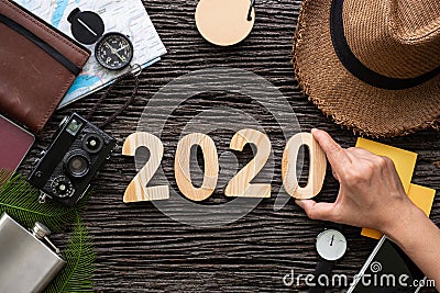 Top view hand putting 2020 happy new year number on wood table with adventure accessory item,holiday vacation planning Stock Photo