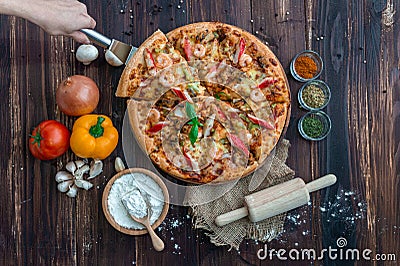 Top view of hand-scoop seafood pizzas and ingredients with garnish on a wooden floor. Stock Photo