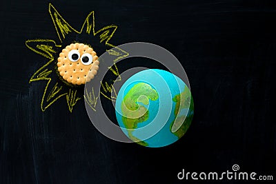 handmade model of Earth planet and cookie Sunwith funny googly eyes on the chalkboard , space and astronomy concept Stock Photo