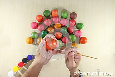 Top view of hands of young man coloring easter eggs with paintbrush on marble top background. Stock Photo