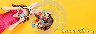 Top view on a happy merry child in bunny ears and a basket with Easter colored eggs. Stock Photo