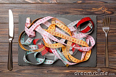 Top view of heap of colorful measuring tapes in plate on wooden background. Diet concept with copy space Stock Photo