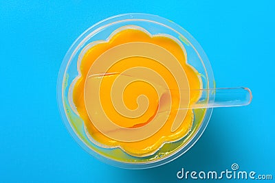 Homemade mango flavor pudding with a spoon on a blue background Stock Photo