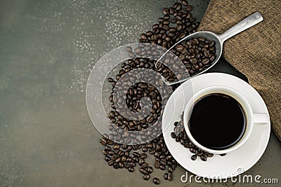 Top view of hot coffee in the white cup with roast coffee beans, bag and scoop on stone table background Stock Photo