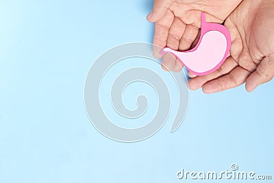 Top view of human hand holding stomach paper cutout. Stomach care, health, healthy digestion and ulcer prevention concept. Stock Photo