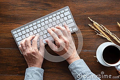 Top view of human hands typing on keyboard, wood desk Stock Photo