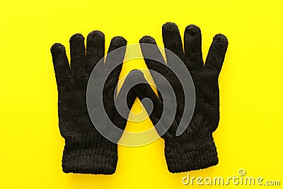 Top view image of black wool gloves over yellow background Stock Photo