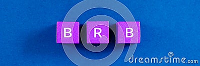 Top view image of BRB spelled on violet wooden dices. Over blue background Stock Photo