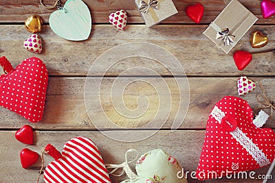 Top view image of colorful heart shape chocolates, fabric hearts and gift boxes on wooden table Stock Photo