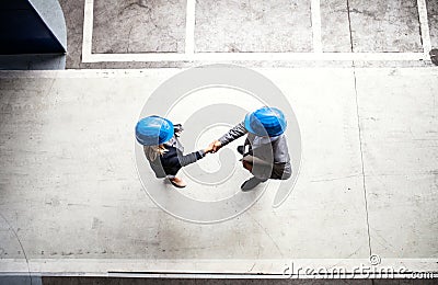 A top view of an industrial man and woman engineer in a factory, shaking hands. Stock Photo