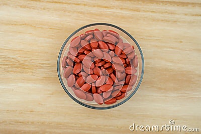 Top view of iron tablets in glass bowl on wood tray with copy space. Use for topics content about treatment anemia Stock Photo