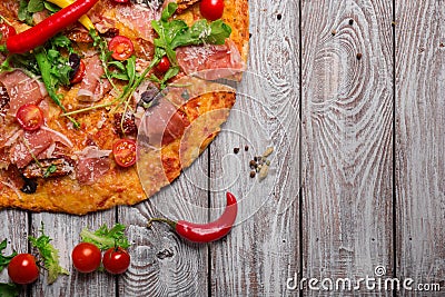 Top view of italian pizza on a rustic table background. A piece of salami pizza with cherry tomatoes and hot chili Stock Photo