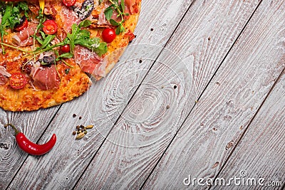 Top view of italian pizza on a rustic table background. A piece of salami pizza with red hot chili pepper. Copy space. Stock Photo