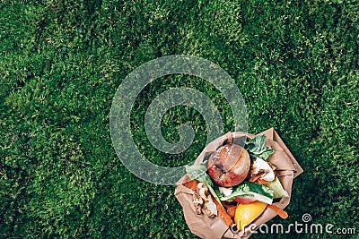 Top view. Kitchen food waste collected in craft paper bag. Peeled vegetables on green grass, moss background Stock Photo