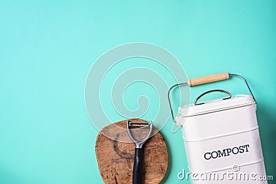 Top view of kitchen food waste collected in recycling compost pot. Peeled vegetables on chopping board, white compost bin on blue Stock Photo