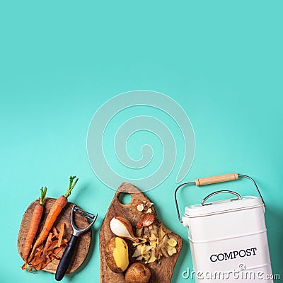 Top view of kitchen food waste collected in recycling compost pot. Peeled vegetables on chopping board, white compost bin on blue Stock Photo