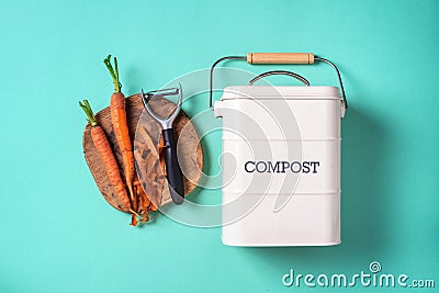 Top view of kitchen food waste collected in recycling compost pot. Peeled vegetables on chopping board, white compost bin on blue Stock Photo