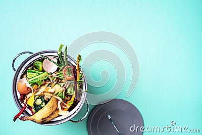 Top view of kitchen food waste collected in recycling compost pot. Peeled vegetables on chopping board, white compost bin on blue Stock Photo