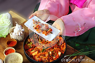 Top view Korean woman in national costume showing her kimchi in white ceramic dish Stock Photo