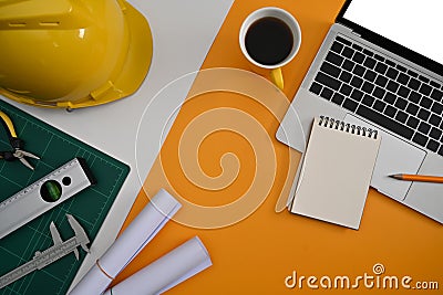 Laptop computer, helmet, blueprints and mechanical tools on Architect workplace. Stock Photo