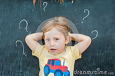 Top view of a little blond kid boy with question mark on blackboard. Concept for confusion, brainstorming and choice Stock Photo