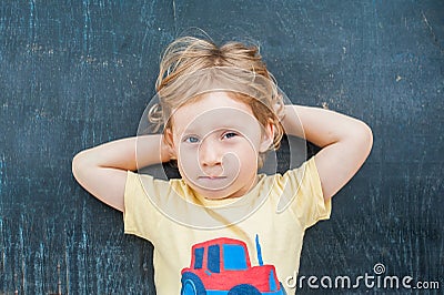Top view of a little blond kid boy with space for text and symbols on the old wooden background. Concept for confusion Stock Photo