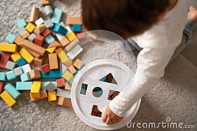 Top view of little toddler boy playing with wooden colorful building blocks sorting shapes Stock Photo