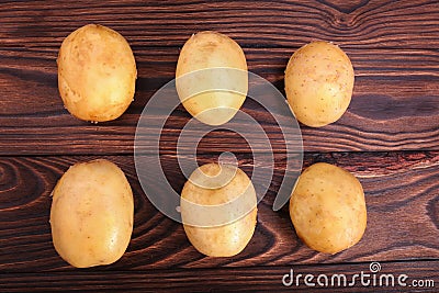 Top view of a lot of fresh and organic potatoes on a dark brown wooden background. New potatoes, close-up. Summer harvest. Stock Photo