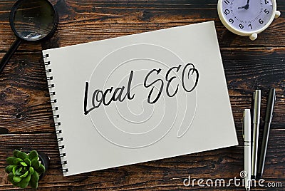 Top view of magnifying glass,clock,pen,plant and notebook written with Local SEO (search engine optimization Stock Photo