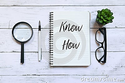 Top view of magnifying glass,glasses,plant,pen and notebook written with Know How on white wooden background. Stock Photo