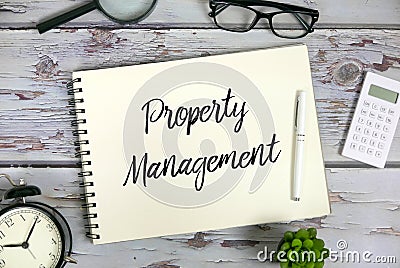 Top view of magnifying glasses,sunglasses,calculator,plant,clock,pen and notebook written with Property Management Stock Photo