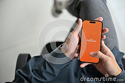 Top view of a man using Payoneer mobile application at his desk. International payments service Editorial Stock Photo