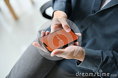 Top view of a man using Payoneer mobile application at his desk. iPhone with Payoneer logo Editorial Stock Photo