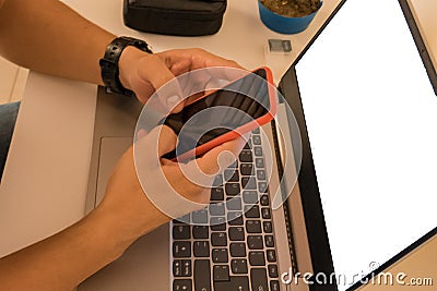 Top view of a man using a smartphone at a white desk. Blank screen laptop for graphical mounting Stock Photo